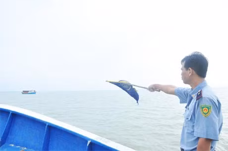 Nhân viên kiểm ngư Việt Nam phất cờ yêu cầu tàu đánh bắt dừng lại để kiểm tra