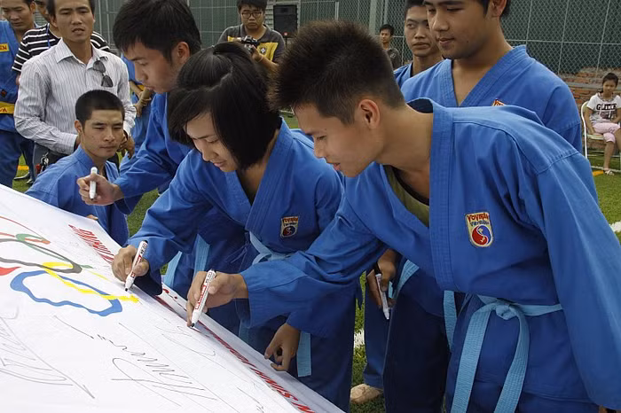 Những môn sinh thay nhau ký tặng vào lá cờ Olympic gửi tới đội tuyển Vovinam quốc gia.