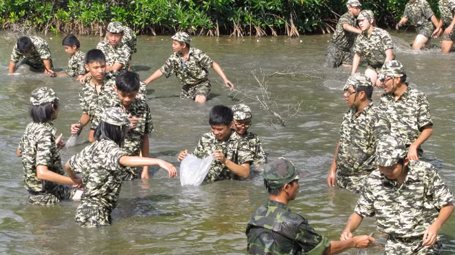 Học viên trải nghiệm kỹ năng sinh tồn của lính đặc công xưa bằng việc đánh lội đầm bắt cá - Ảnh: Q.LINH