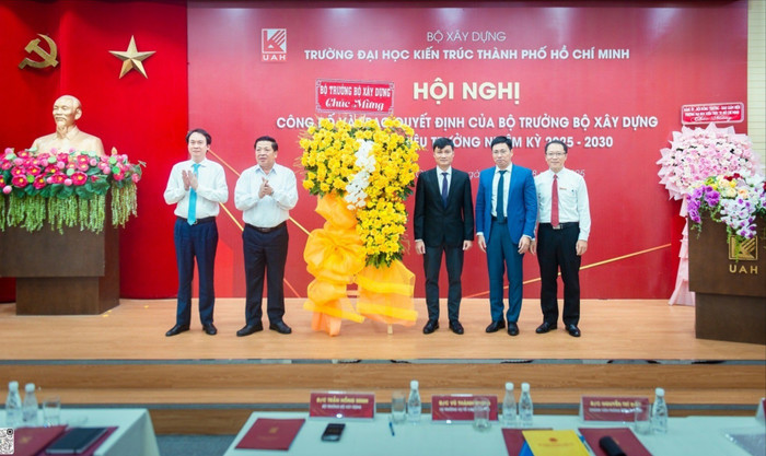 Bộ trưởng Trần Hồng Minh và Vụ trưởng Vụ Tổ chức cán bộ Vũ Thành Trung tặng hoa chúc mừng tập thể lãnh đạo nhà trường. Ảnh: website nhà trường. 542319677-1580722642900625-689149658684455250-n-2207-2824.jpg