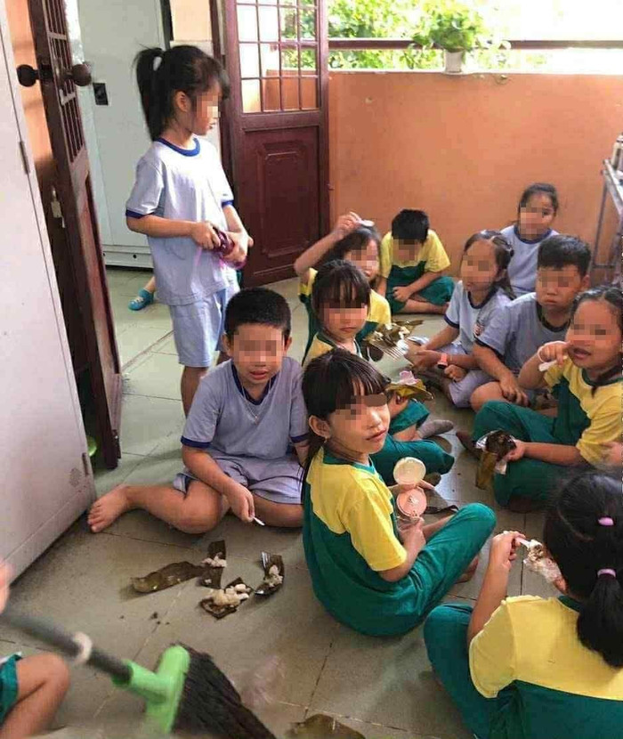 Một số học sinh Trường tiểu học Hiệp Thành ngồi ăn đầu giờ chiều ngày 7/10 dưới đất. Ảnh do phụ huynh cung cấp. hsthhiepthanhngoianduoidatb.jpg