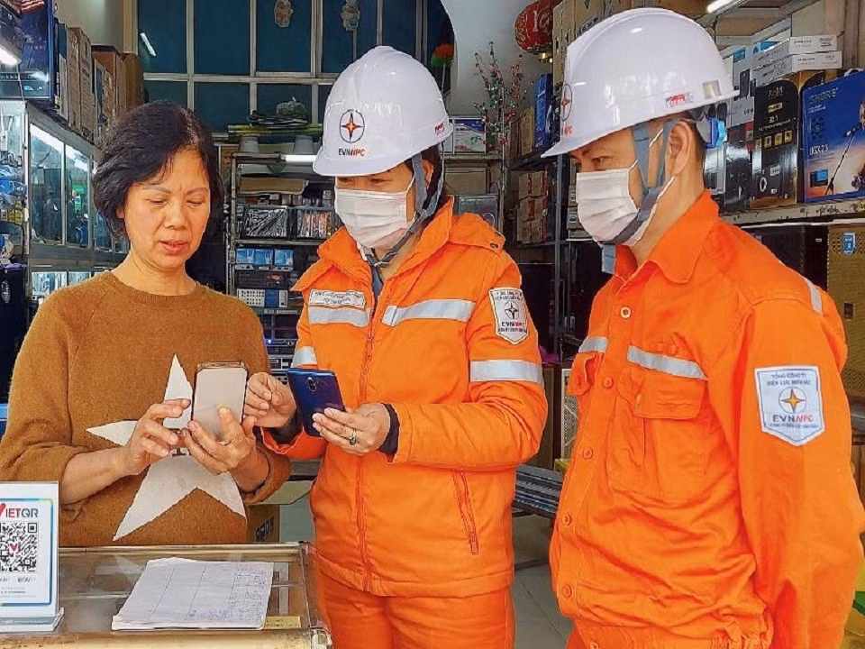 Nhân viên của EVNNPC hướng dẫn khách hàng thanh toán hóa đơn điện qua điện thoại di động