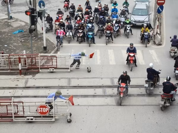 Dù đã có có tín hiệu và nhân viên kéo ba-ri-e chắn tàu nhưng nhiều người vẫn bất chấp lao qua. ảnh: TTXVN.