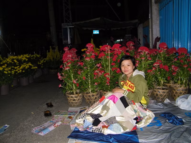 Cô gái tên My đang thức canh những chậu hoa, thay phiên cho người chị mình đang ngủ. Ảnh chụp trước cổng trường THCS Lê Lợi (ngã 6 Dân Chủ, Q3).