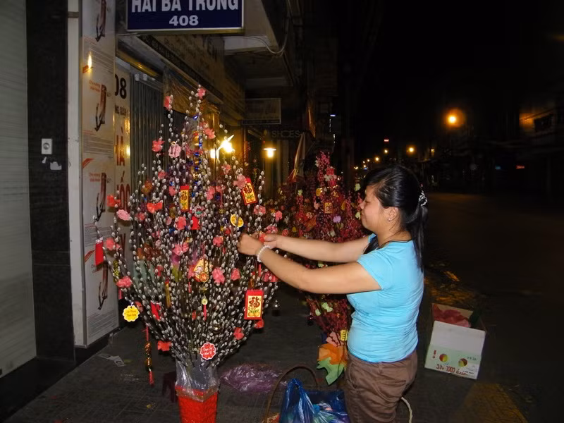 Trên con đường Hai Bà Trưng (Q1) đã vắng xe qua lại, Kim Thanh vừa canh hàng, vừa tranh thủ trang trí những nhành đào của mình cho kịp trời sáng.
