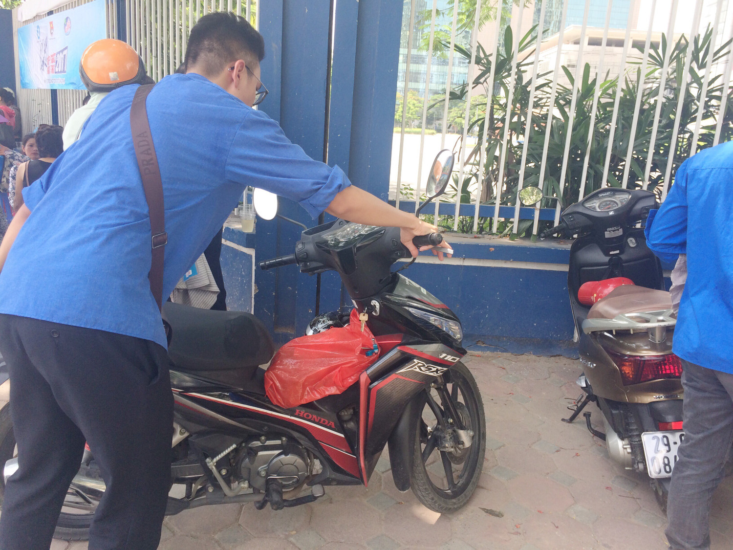 Hình ảnh bạn thanh niên tận tình dắt xe vào bãi gửi miễn phí giúp các bác phụ huynh. (Ảnh: Ngọc Bích) Hình ảnh bạn thanh niên tận tình dắt xe vào bãi gửi miễn phí giúp các bác phụ huynh. (Ảnh: Ngọc Bích)