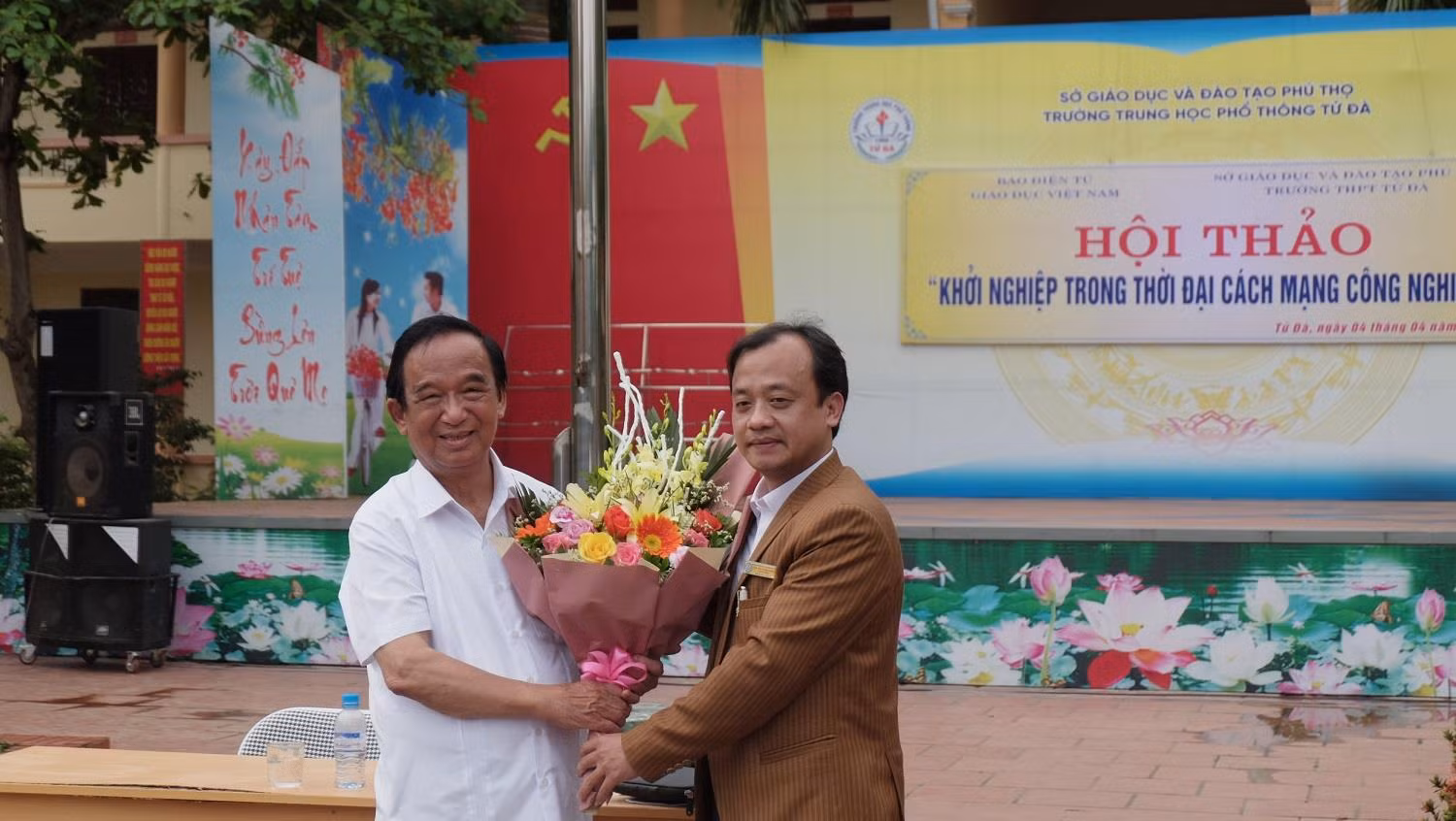 Đại diện trường Trung học phổ thông Tử Đà, thầy giáo Bùi Tuấn Long tặng hoa Nhà giáo nhân dân Nguyễn Lân Dũng. (Ảnh: LC)