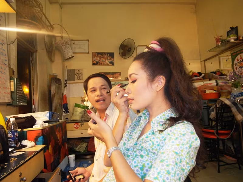 Trong lúc Trịnh Kim Chi hoá trang, diễn viên Văn Ruy vẫn quay qua đùa: “Con nhỏ… ác hậu (á hậu) này có tay nghề làm đẹp siêu đẳng lắm đó”.