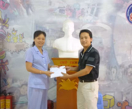 Bà Đinh Thúy Hiền, đại diện lãnh đạo trường Mầm non thực hành Hoa Hồng trao tiền và vật phẩm cho ông Bùi Ngọc Cải, Phó Tổng biên tập báo điện tử Giáo dục Việt Nam.