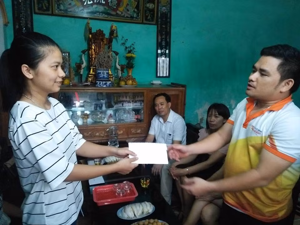 Ông Nguyễn Văn Thiện (bên phải) đại diện các nhà hảo tâm trao quà cho em Đặng Thị Thương. Ảnh của Thanh Minh.
