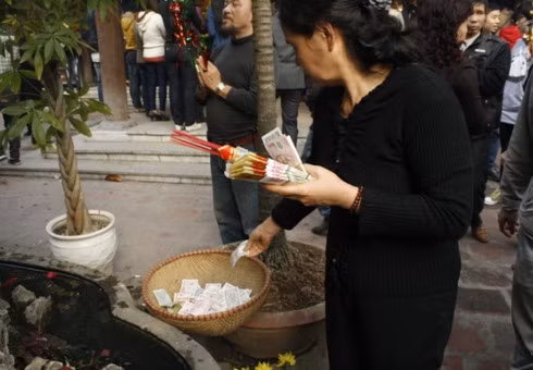Ở chùa Hà (Cầu Giấy), người ta đặt tiền bất cứ đâu: trên cây, hòn non bộ, ném xuống ao… vì thế nhà chùa phải huy động cả những chiếc rổ đặt tại một số điểm ở sân chùa. Ảnh chụp chiều 16 tháng Giêng âm lịch.