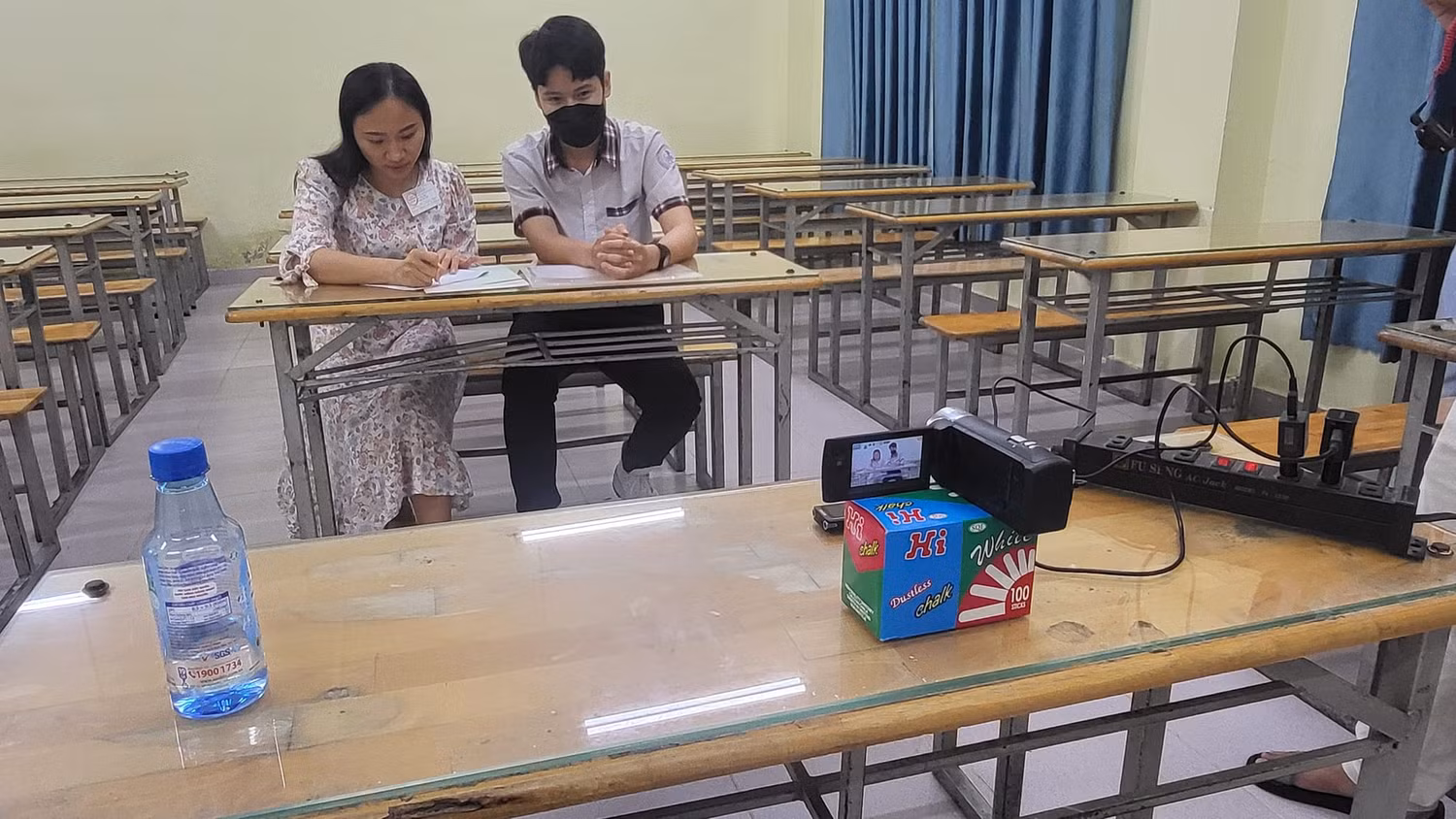 Thí sinh Long và cán bộ hỗ trợ ghi bài, có thiết bị ghi hình ghi âm giám sát (ảnh: P.L)