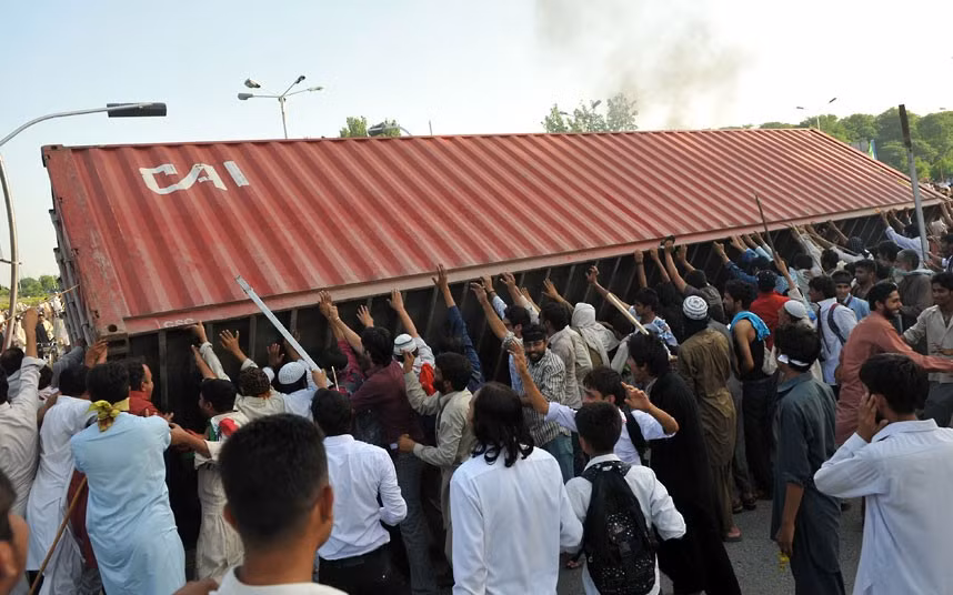 Đám đông lật đổ container vận chuyển hàng hóa được cảnh sát đặt để làm rào chắn ngăn chặn con đường vào Đại sứ quán Mỹ.