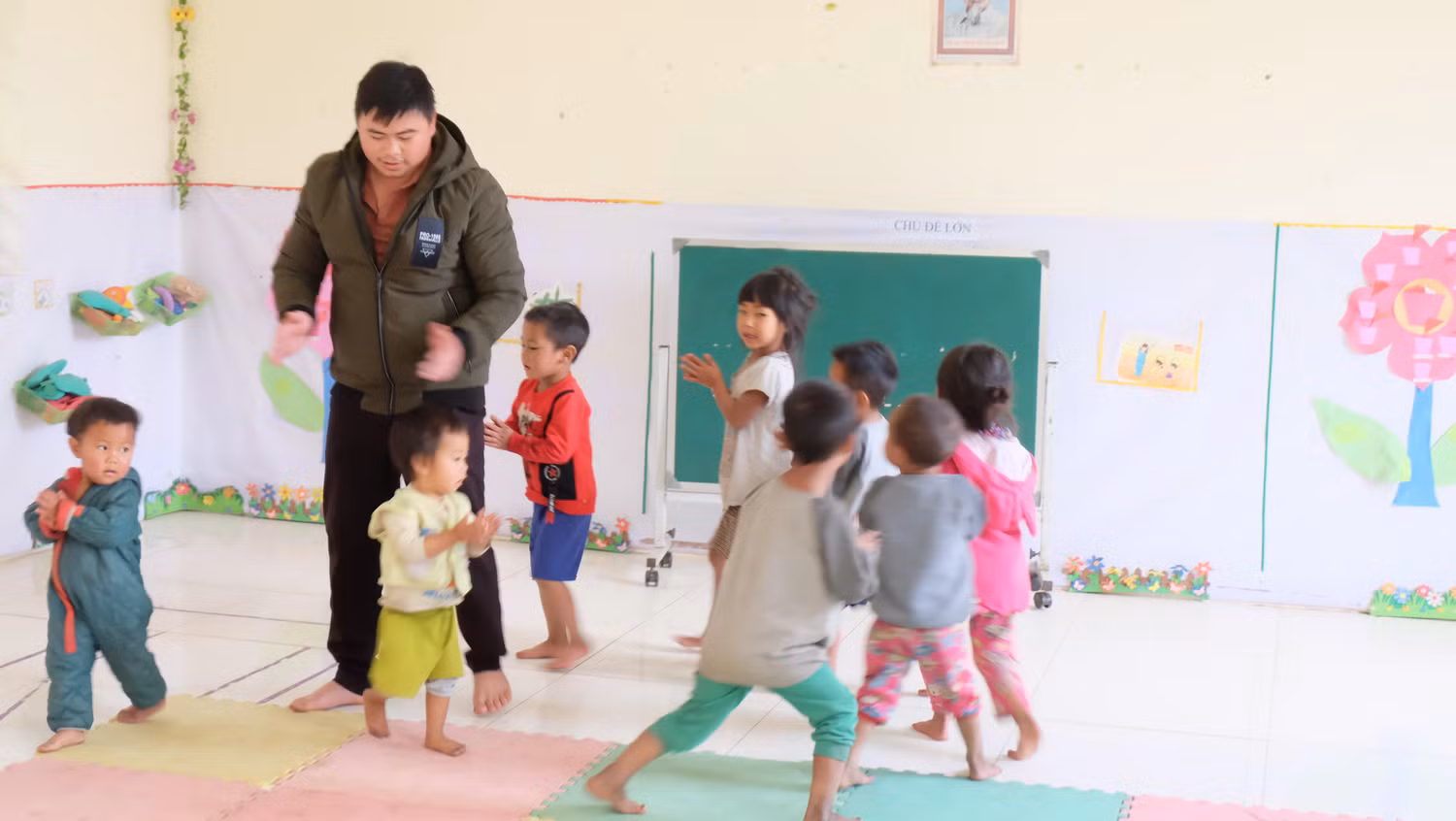 "Ông bố" mầm non với những đứa trẻ đang múa hát, học các bài học đầu đời của lũ trẻ. Ảnh: LC