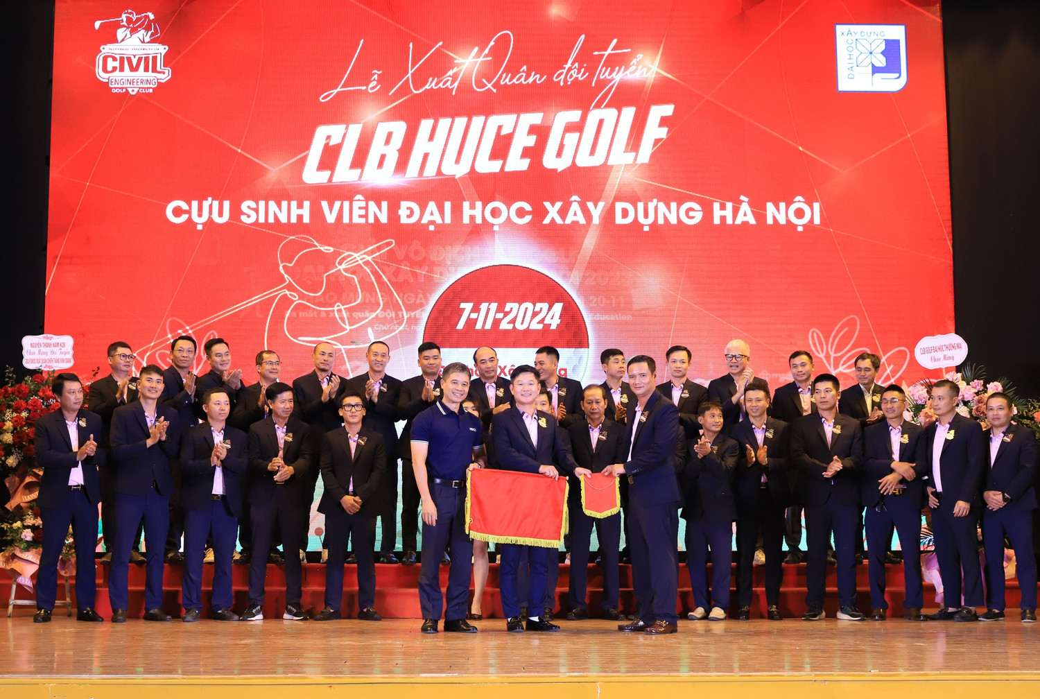 Hiệu trưởng Trường Đại học Xây dựng Hà Nội thực hiện nghi thức trao cờ xuất quân và băng đeo cho đại diện Đội tuyển Câu lạc bộ HUCE golf Cựu sinh viên Trường Đại học Xây dựng Hà Nội. Ảnh: HUCE.