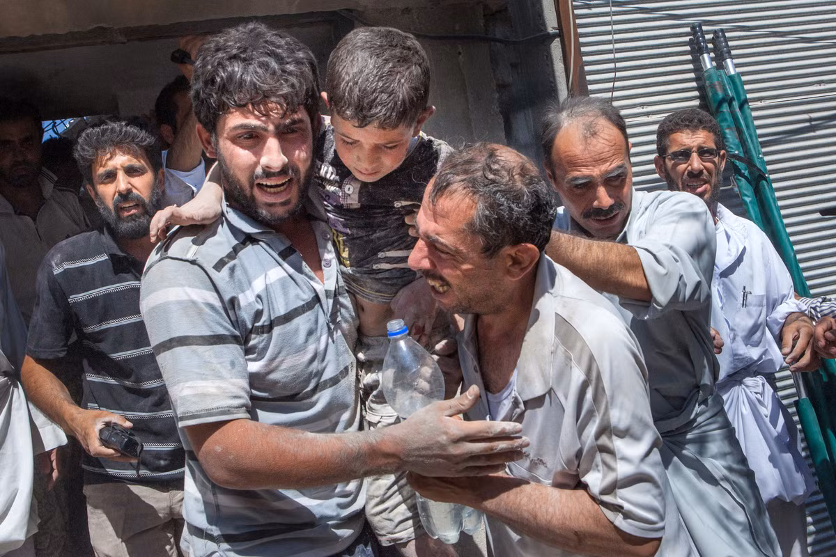 Các tình nguyện viên Syria khóc sau khi giải cứu được bé Fayad Mahmud 8 tuổi.