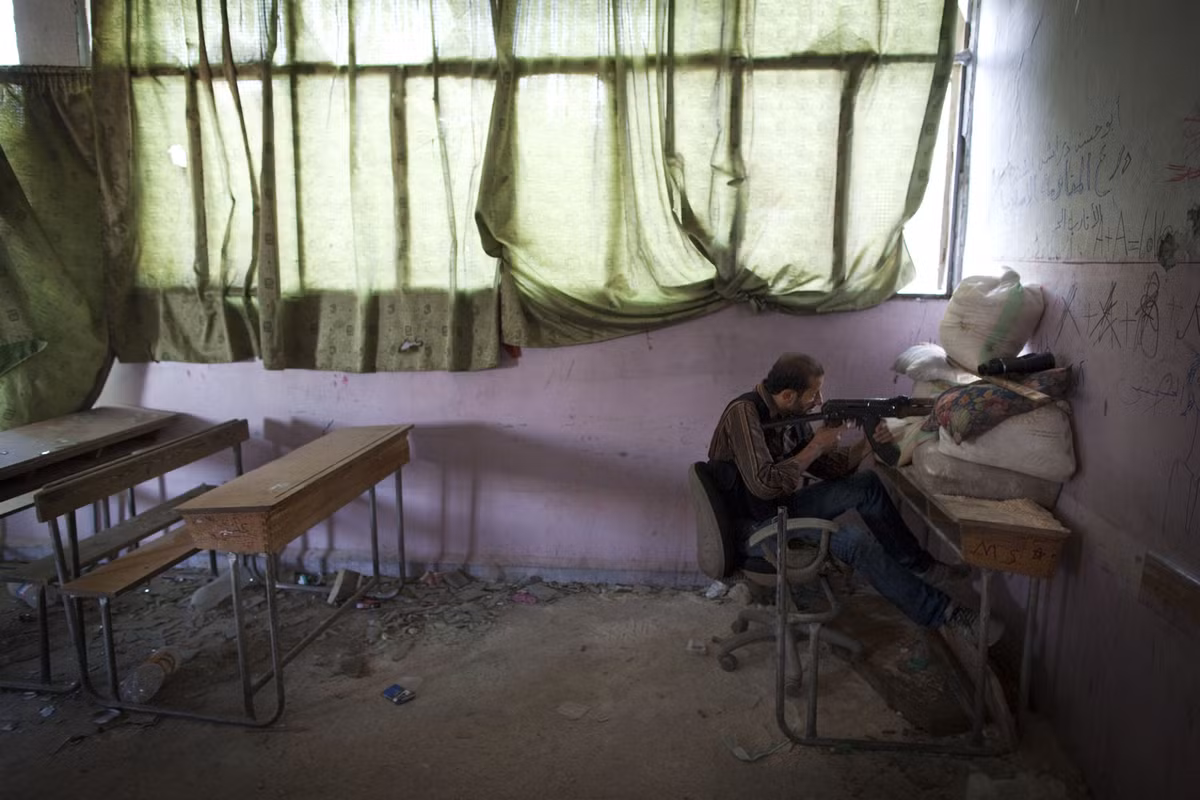 Một tay súng nổi dậy ngắm bắn lực lượng chính phủ Syria trong một trường học bị phá hủy ở quận Izaa, Aleppo, vào ngày 14/7.