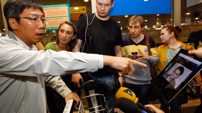 Một nhà báo chỉ cho hành khách đến từ Hồng Kông xem hình của Snowden tại sân bay quốc tế Sheremetyevo, Moscow hôm 23/6 để tìm hiểu xem anh có mặt trên chuyến bay của họ hay không. Một nhà báo chỉ cho hành khách đến từ Hồng Kông xem hình của Snowden tại sân bay quốc tế Sheremetyevo, Moscow hôm 23/6 để tìm hiểu xem anh có mặt trên chuyến bay của họ hay không.