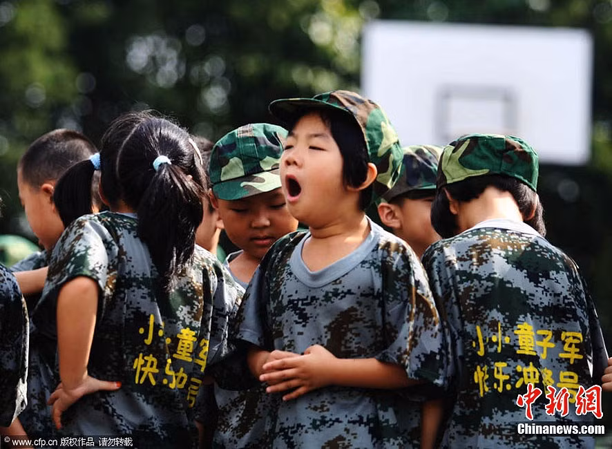 Một bé còn đang ngáp ngủ trong khi bạn bè cùng lớp làm quen với nhau