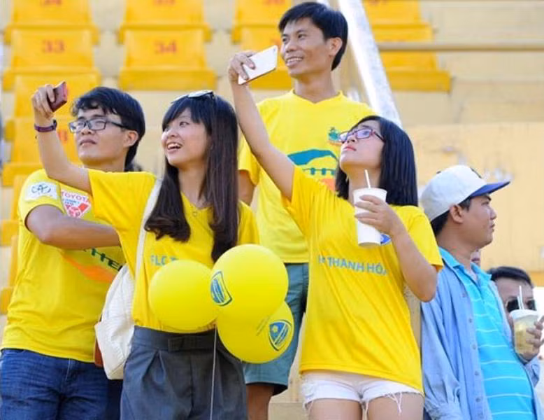 CĐV nữ nhí nhảnh selfie trên khán đài trước trận đấu.