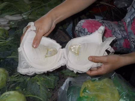 Thấy cợm cợm khó chịu, chị Oanh dùng dao mổ ra phát hiện có 2 gói dung dịch màu trắng chứa 6 viên thuốc. (Ảnh: Hồng Sơn)