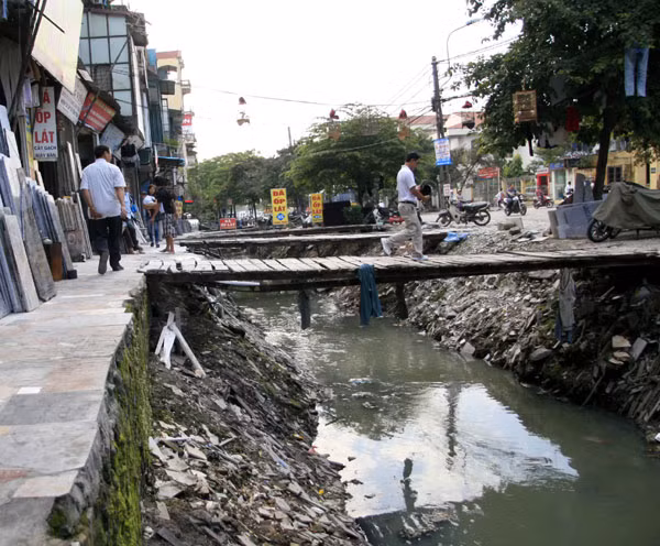 Người lớn có vẻ đơn giản hơn khi băng qua những chiếc cầu ọp ẹp làm tạm bợ để sang bên kia đường