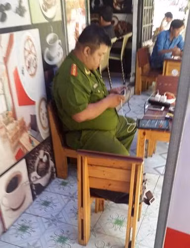 Thiếu tá Vĩnh ngồi chơi game bằng điện thoại trong quán cà phê khi còn là giờ làm việc (ảnh: P.L) Thiếu tá Vĩnh ngồi chơi game bằng điện thoại trong quán cà phê khi còn là giờ làm việc (ảnh: P.L)