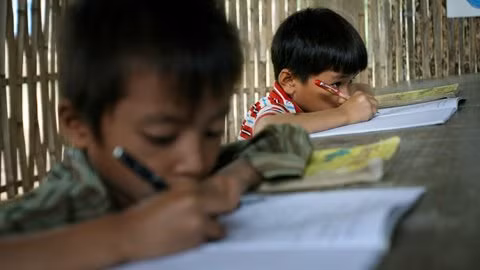 Cũng giống như học sinh ở Trường Nguyễn Bá Ngọc, những học sinh lớp 1 ở điểm Trường Khe Bốc thuộc Trường Tiểu học số 2 Điện Quan (Xã Điện Quan, Bảo Yên, Lào Cai) cũng phải ngồi học trên những bộ bàn ghế mà mặt bàn cao ngang cổ. Với tư thế ngồi viết thế này kéo dài không mắc những tật bệnh về mắt, cổ mới lạ.