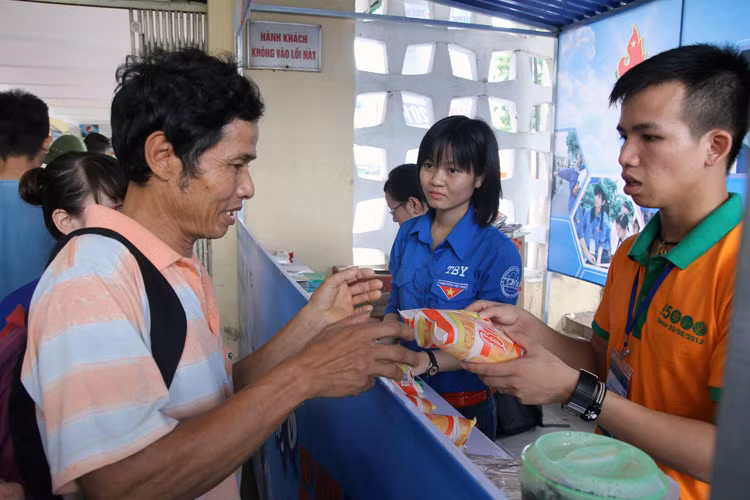 Tại các bến xe Hà Nội, lực lượng sinh viên tình nguyện triển khai giúp đỡ sĩ tử, người nhà, góp phần nào xua đi nỗi lo. Trong ảnh là người nhà sĩ tử nhận bánh mỳ miễn phí tại Bến xe phía Nam.
