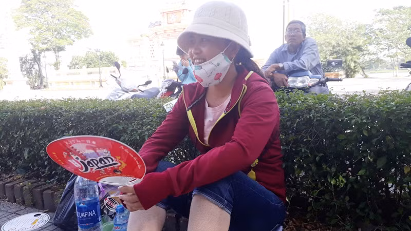 Thời tiết nắng nóng nên phụ huynh phải ngồi ở các bóng cây ven đường. Ảnh: TL