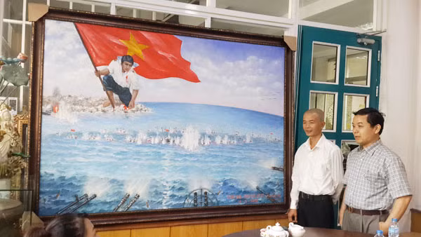Họa sĩ Bùi Lệ Trang (trái) và ông Nguyễn Văn Phước - Giám đốc First News giới thiệu bức tranh “Gạc Ma - Vòng tròn bất tử”. (Ảnh: cand.com.vn)