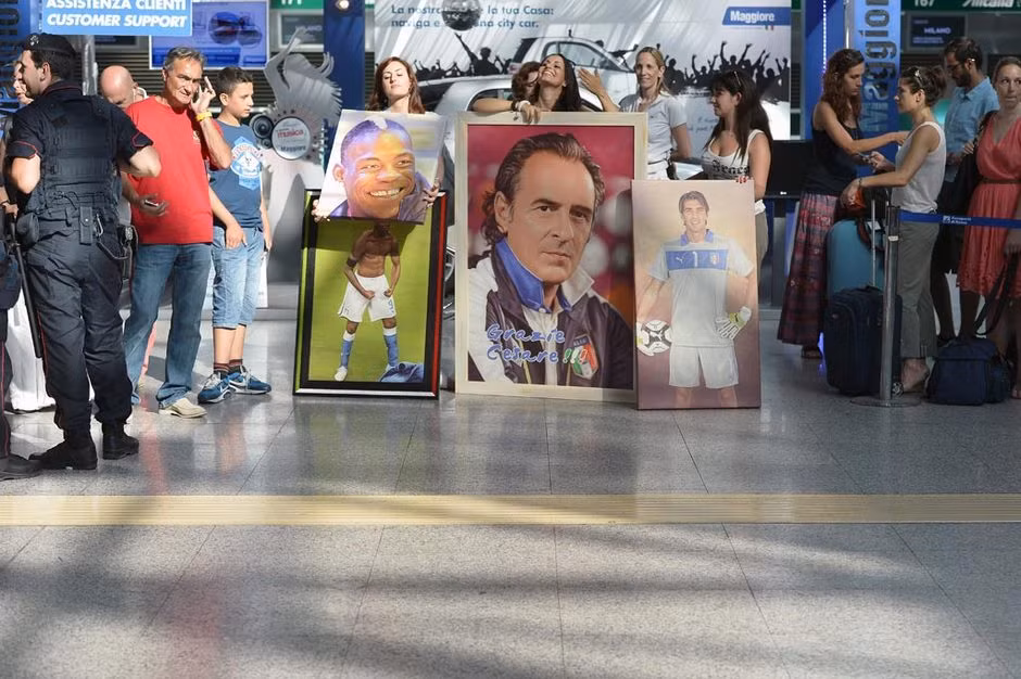 Các cô gái xinh đẹp mang theo tấm poster lớn in hình Balotelli, HLV Prandelli và thủ thành Buffon để chào đón đội tuyển Italia bên ngoài sân bay