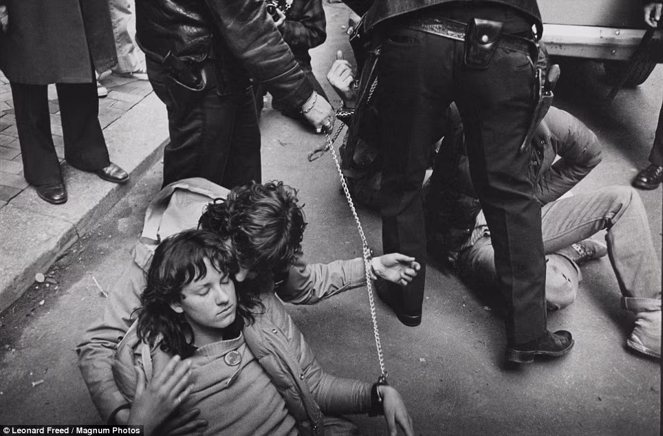 Năm 1979: cảnh sát New York bắt giữ những người biểu tình chính trị trẻ tuổi đang nằm trên đường phố trong tình trạng bị còng tay. Năm 1979: cảnh sát New York bắt giữ những người biểu tình chính trị trẻ tuổi đang nằm trên đường phố trong tình trạng bị còng tay.