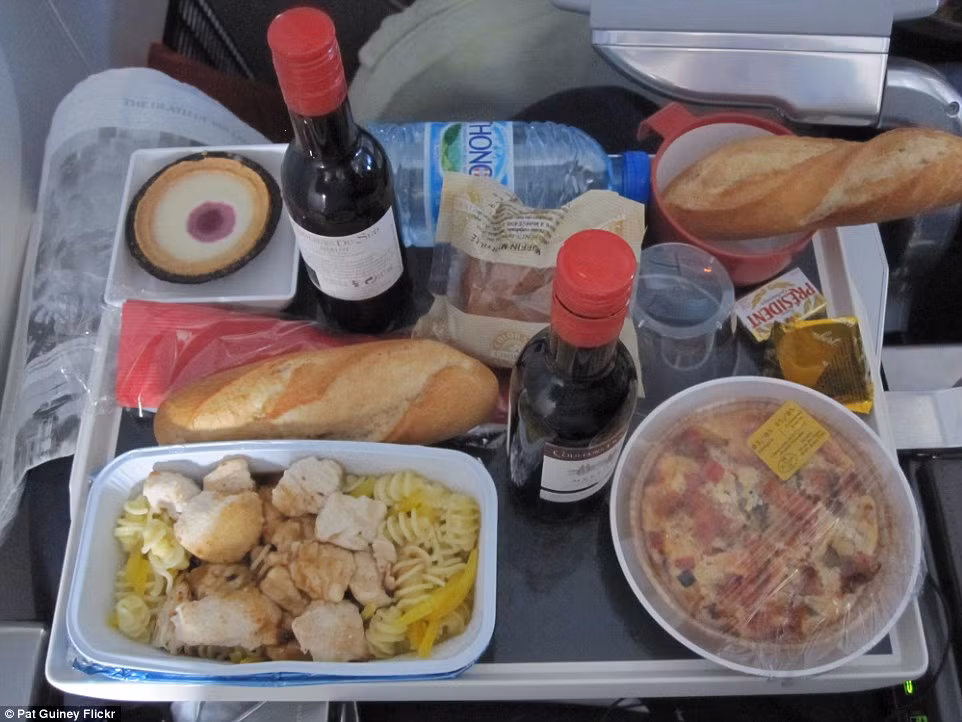 Bữa ăn của Air France có mì xào gà, rượu vang đỏ, bánh mì, chai nước và bánh ngọt để tráng miệng.