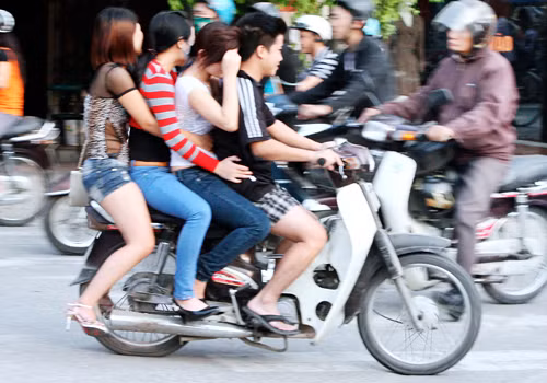 Bốn người không đội mũ bảo hiểm ngồi trên chiếc xe máy. Chụp trên đường Kim Ngưu - Hà Nội. Ảnh: Hoàng Anh Dũng.