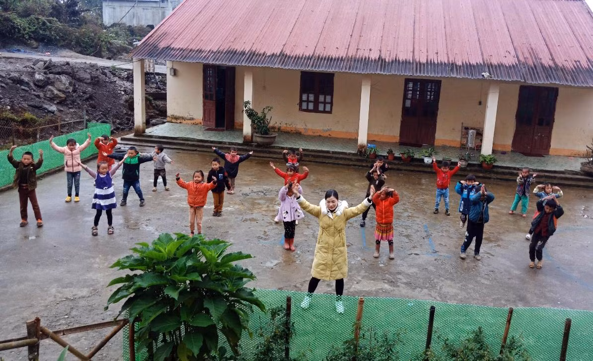 Cô Lồ Thị Lan, người dân tộc Bố Y - Giáo viên dạy lớp 1 Trường Tiểu học số 2 thị trấn Mường Khương, tỉnh Lào Cai và các em học sinh trong giờ thể dục. Ảnh: Nhân vật cung cấp.