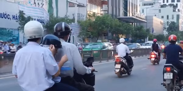 Hai em học sinh ăn vội cơm hộp trên đường (Ảnh từ clip, nguồn: Vietnamnet.vn)