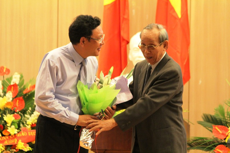 Bộ trưởng Bộ GD&amp;ĐT Phạm Vũ Luận nhận hoa từ GS. Trần Hồng Quân - Chủ tịch Hiệp hội các trường Đại học, Cao đẳng Việt Nam trong một hội nghị. Ảnh Xuân Trung