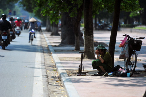 Người bơm xe đạp thu mình dưới tán lá cây lưa thưa để tránh nắng. Người bơm xe đạp thu mình dưới tán lá cây lưa thưa để tránh nắng.