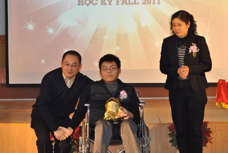 Cù Hữu Hoàng chụp ảnh lưu niệm cùng Phó hiệu trưởng Trường ĐH FPT Nguyễn Xuân Phong và mẹ trong lễ vinh danh Cóc vàng.