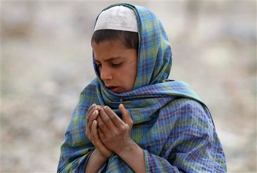 Một cậu bé người Afghanistan đang cầu nguyện bên mộ thân nhân chết trong vụ thảm sát. Ảnh: AP