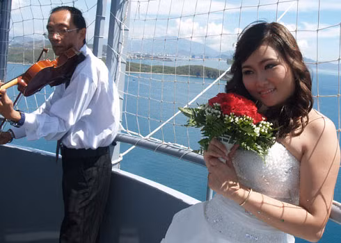 Cô dâu bẽn lẽn khi được người nhạc công chơi bản nhạc chúc mừng. Ảnh: Khuê Việt Trường, VnExpress