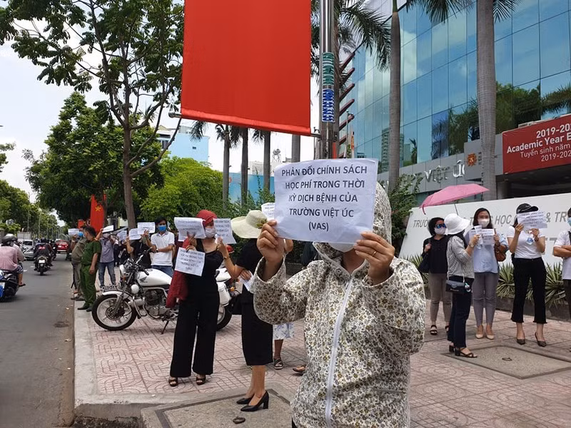 Phụ huynh Trường dân lập Quốc tế Việt Úc (Thành phố Hồ Chí Minh) cầm biểu ngữ đứng trước cổng trường yêu cầu đối thoại với lãnh đạo Trường về vấn đề học phí của học sinh. (Ảnh: baophapluat.vn)