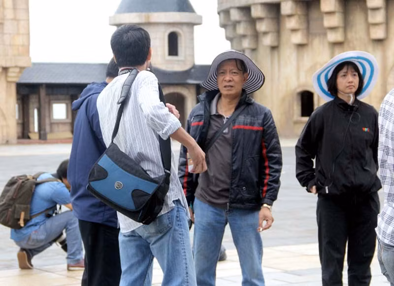 Đạo diễn Lại Văn Sâm đội mũ rộng vành, mặc áo khoác trao đổi công việc với đồng nghiệp.