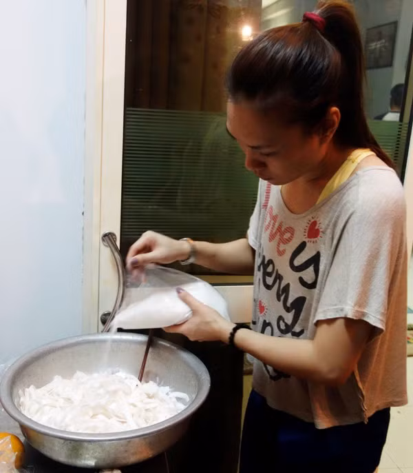 Trộn đường vào những miếng cái dừa đã cắt nhỏ, chuẩn bị làm món mứt dừa.