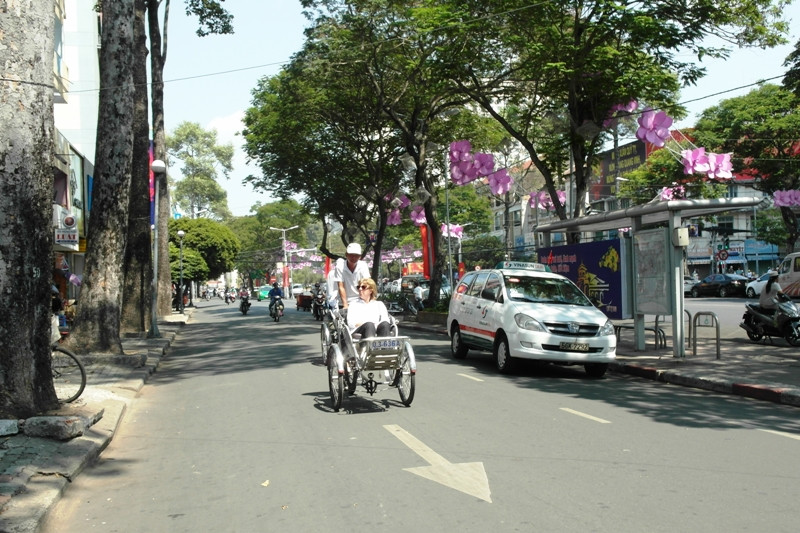 Du khách nước ngoài thảnh thơi ngồi xích lô ngắm cảnh trên con đường Lê Lợi (Quận 1) rộng thênh thang.